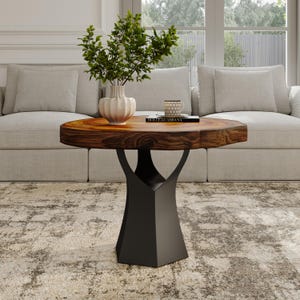 May include: A round wooden coffee table with a black metal base. The table top has a natural wood grain pattern and is slightly irregular in shape. The base is a geometric shape with a wide, flat bottom and a narrow, pointed top.