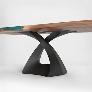 May include: A modern wooden table with a dark finish and a unique, sculptural base. The tabletop features a natural wood grain with a blue resin inlay. The base is made of black metal and has an X-shaped design.