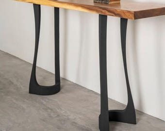 May include: A wooden console table with a natural wood top and black, curved legs. The table has a long, rectangular shape and is decorated with vases and a small book. The table is designed for a living room or entryway.