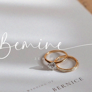 May include: Two gold wedding bands with a single diamond ring on a white card with the text "Bemine Jewelry" and "Wedding of Bernice".