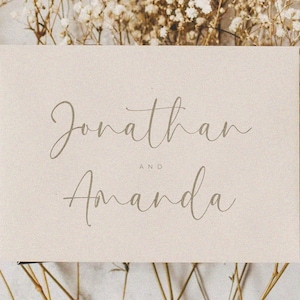 May include: A simple, elegant wedding announcement card with the names "Jonathan and Amanda" written in a cursive script font on a beige background.