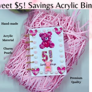 May include: A pink acrylic binder with gold rings, featuring a teddy bear design and the text "Sweet $5! Savings." The binder is adorned with charm pearls and heart-shaped accents. The words "Hand-made," "Acrylic Material," and "Premium Quality" are also visible.