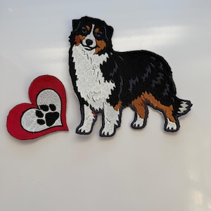 May include: Embroidered patch set featuring an Australian Shepherd dog and a red heart with a paw print. The dog patch is black, white, and brown. The heart has a red border and a white center with a black paw print.