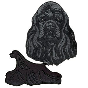 May include: Two black embroidered patches featuring a Cocker Spaniel. One patch is a detailed head portrait, and the other depicts the dog's body in a stylized pose. The patches are on a white background.
