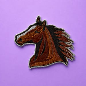 May include: An embroidered iron-on patch featuring the profile of a brown horse head with a black mane and a white blaze on its forehead. The patch has a silver-colored stitched border and is shaped to follow the outline of the horse's head.