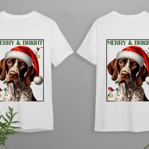 May include: Two white t-shirts with a graphic of a German Shorthaired Pointer wearing a Santa hat and surrounded by Christmas lights. The text "Merry & Bright" is above the dog.