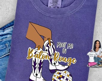 May include: Purple t-shirt with a graphic of a woman wearing cowboy boots and a disco ball. The text on the shirt reads "Meet me in Baton Rouge".