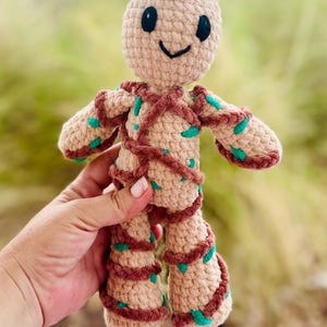 Puede incluir: Un juguete de peluche tejido a crochet de un personaje de la película Guardianes de la Galaxia. El juguete es marrón con detalles verdes y tiene una cara sonriente.
