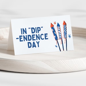 Peut inclure: Une carte blanche avec du texte bleu et rouge qui dit "In "Dip" -endence Day". La carte a un graphique de trois feux d'artifice rouge, blanc et bleu.
