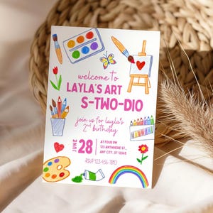 May include: A white invitation card with colorful illustrations of art supplies, including paint palettes, brushes, and pencils. The card reads "welcome to LAYLA'S ART S-TWO-DIO" and includes details for a birthday party on June 28th.