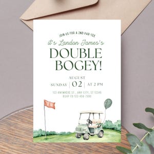 May include: A white invitation card with green text that reads "JOIN US FOR A 2ND PAR-TEE, it's Landon James's DOUBLE BOGEY!" with event details. Features a watercolor illustration of a golf cart, flag, and balloon.