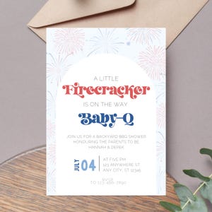 Peut inclure: Une invitation de fête prénatale bleue et rouge avec un motif de feux d'artifice. Le texte indique "A Little Firecracker is on the way Baby-Q". L'invitation comprend la date "July 04" et l'heure "At Five PM".