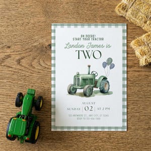 May include: A green toy tractor sits next to a birthday invitation with a watercolor illustration of a tractor. The invitation has the text "Oh Deere! Start Your Tractor" and "Landon James is TWO". The invitation is bordered with a green and white gingham pattern.