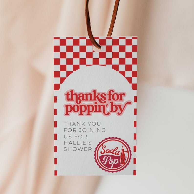 May include: A rectangular gift tag with a red and white checkered pattern at the top. The tag features the text "thanks for poppin' by" in pink lettering. Below, it reads "THANK YOU FOR JOINING US FOR HALLIE'S SHOWER" and includes a "Soda Pop" logo.