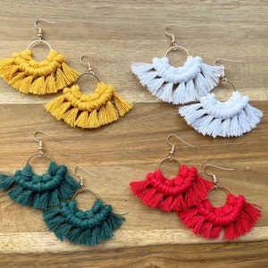 May include: Four pairs of handmade macrame earrings with gold hoops. The earrings are in four colors: yellow, white, green, and red.