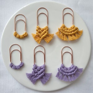 以下が含まれることがあります： 金色のフープが付いた、手作りのマクラメイヤリングが6ペア。3ペアは黄色、3ペアは紫色です。