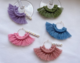 May include: Five gold hoop wine glass charms with colorful tassels and white beads with gold lettering spelling out the names "Iris", "Angela", "Mom", and "SMS".
