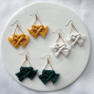 May include: Four pairs of handmade macrame earrings. Two pairs are yellow, one pair is white, and one pair is green.