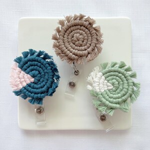 May include: Three colorful woven badge holders with fringe. Each holder is attached to a clear plastic retractable badge reel.
