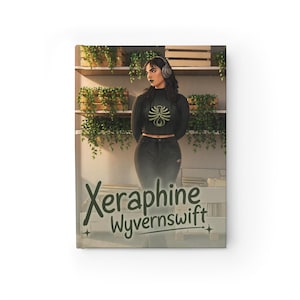 May include: A hardcover journal with the title "Xeraphine Wyvernsift" in green script. The cover features a person wearing a black sweater and jeans, with headphones, in front of a shelf with plants. The journal is rectangular.