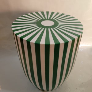 May include: A green and white striped round stool with a sunburst design on the top.