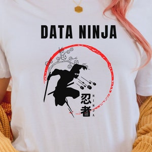 Może przedstawiać: Biała koszulka z czarną sylwetką ninja rzucającego gwiazdami ninja. Tekst "DATA NINJA" znajduje się nad ninja, a japońskie słowo oznaczające ninja znajduje się pod ninja w czerwonym kółku.