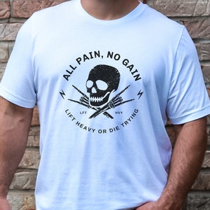 May include: White t-shirt with a black skull and crossbones graphic. The graphic says "All Pain, No Gain" and "Lift Heavy or Die Trying".