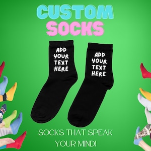May include: Two black socks with white text that says "Add your text here". The socks are on a green background with other colorful socks in the background. The text "CUSTOM SOCKS" is at the top of the image in blue and pink letters. The text "SOCKS THAT SPEAK YOUR MIND!" is at the bottom of the image.