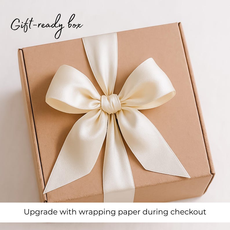 May include: A brown cardboard gift box with a white satin ribbon tied in a bow. The box has the text "Gift-ready box" printed on the top. The text "Upgrade with wrapping paper during checkout" is printed below the box.