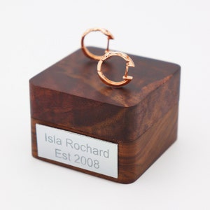 Puede incluir: Un par de pendientes de aro de oro rosa en una caja de madera con una placa de plata que dice "Isla Rochard Est 2008".
