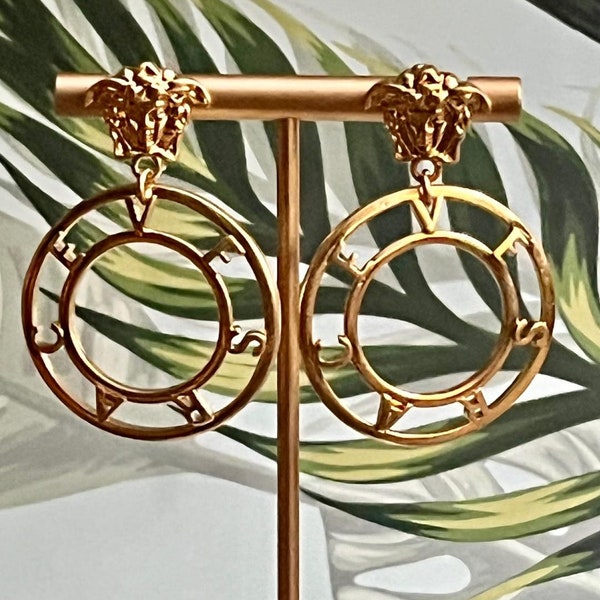 Double Trouble Chic: With double circles and Versace script, these earrings redefine hoop earring style.