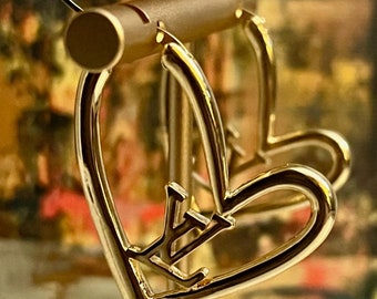 Louis Vuitton irregularly shaped heart earrings with center LV insignia.