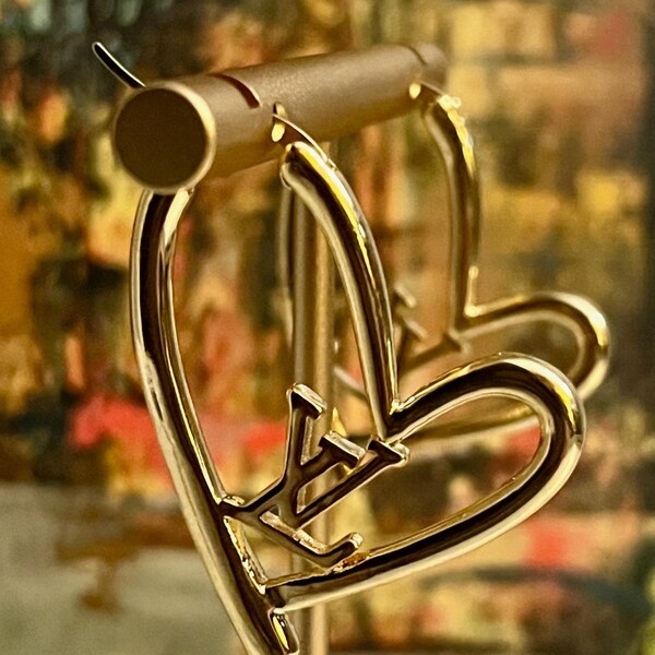 Louis Vuitton irregularly shaped heart earrings with center LV insignia.