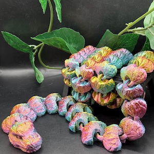 May include: A collection of colorful, abstract sculptures in shades of pink, yellow, blue, and green. The objects have a textured, organic appearance and are arranged in a decorative display. The sculptures are likely made of a 3D-printed material.