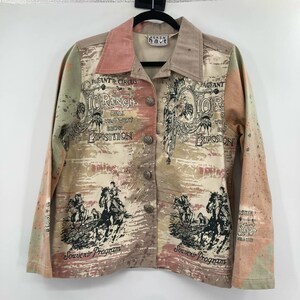 May include: A beige, pink and green long-sleeved button-up shirt with a western theme. The shirt features a faded print of horses, cowboys, and the text "10 Ranch Real Wild West Show Exposition" and "Souvenir Program".