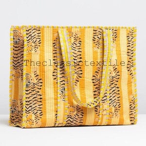 May include: A yellow and orange tote bag with a striped pattern and tiger print. The bag has two handles and is made of quilted fabric.