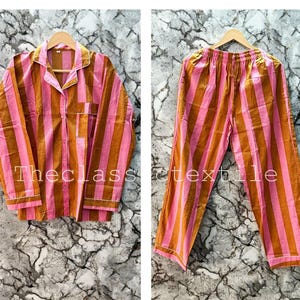 Può includere: Un pigiama a righe rosa e marrone con una parte superiore con bottoni e pantaloni abbinati. Il set è realizzato in morbido cotone ed è perfetto per rilassarsi a casa.