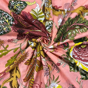 May include: Pink fabric with a floral print featuring pink, yellow, and green flowers, leaves, and vines. The fabric has a textured, wrinkled appearance.