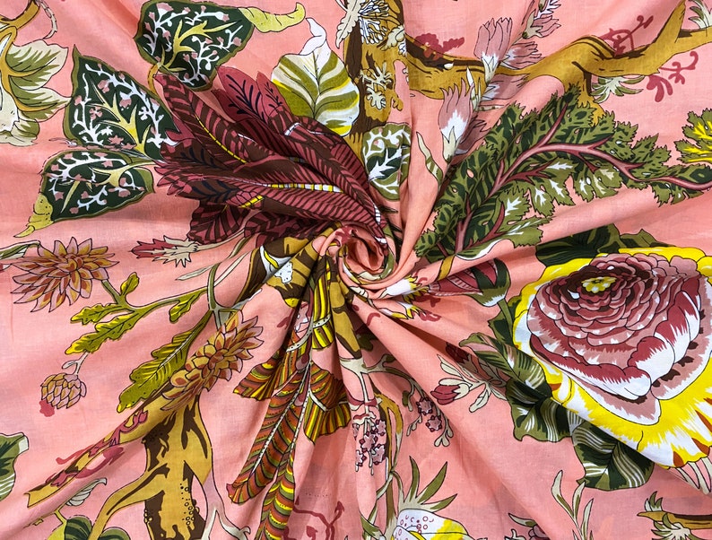 May include: Pink fabric with a floral print featuring pink, yellow, and green flowers, leaves, and vines. The fabric has a textured, wrinkled appearance.