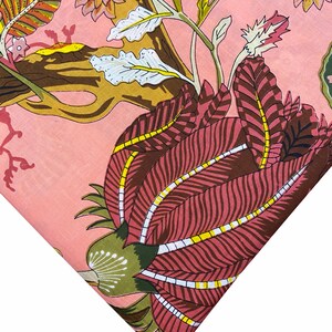 May include: Pink fabric with a floral print featuring a large pink flower with yellow and white accents, and smaller flowers in shades of brown and pink.