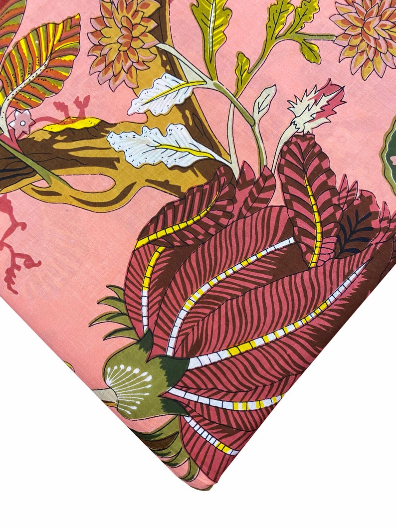 May include: Pink fabric with a floral print featuring a large pink flower with yellow and white accents, and smaller flowers in shades of brown and pink.