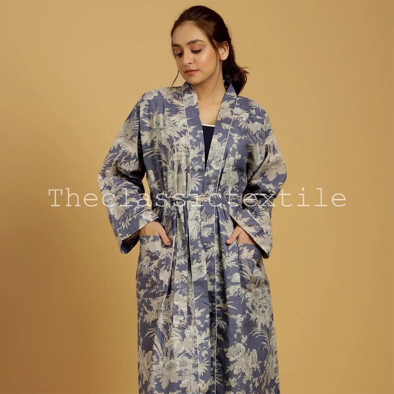 May include: A long, blue floral robe with a white floral pattern. The robe has a tie belt and two pockets. The text "The Classic Textile" is visible in the lower left corner of the image.