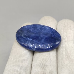 May include: A smooth, oval-shaped blue sodalite stone with white veining. The stone is polished and has a glossy finish.