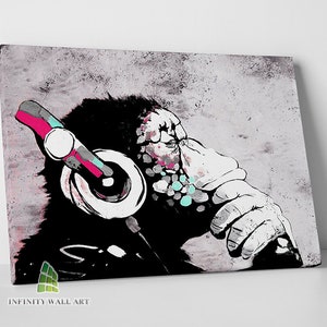 May include: A canvas print depicting a chimpanzee wearing headphones in a stylized manner. The artwork uses a black, white, grey, pink, and teal colour palette. The chimpanzee is in a relaxed pose, with one hand near its face. The text "INFINITY WALL ART" is at the bottom.