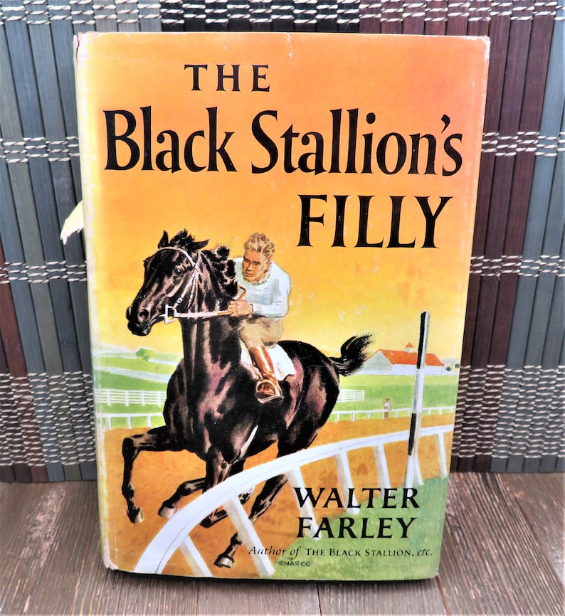 Puede incluir: Una portada de libro vintage con un caballo negro corriendo en una pista con un jinete montando. El t&iacute;tulo es "The Black Stallion's Filly" de Walter Farley, autor de "The Black Stallion".
