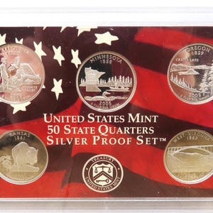 May include: A United States Mint 50 State Quarters Silver Proof Set in a clear plastic case. The set includes five quarters, each featuring a different state design. The background has a red and white flag design.
