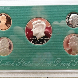 May include: A 1996 United States Mint Proof Set. The set includes a silver dollar, a half dollar, a quarter, a dime, and a nickel. The coins are all in proof condition, which means they have a mirror-like finish.