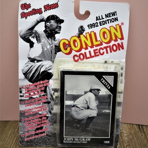 May include: A vintage-style baseball card featuring a black and white photo of John McGraw, a baseball manager, in a crouching pose. The card is part of the Conlon Collection, a 1992 edition of 330 baseball cards featuring photography of Charles Conlon. The card has the text "TRIVIA" in the top right corner and "JOHN MCGRAW MANAGER WITHOUT PEER 1909" at the bottom.