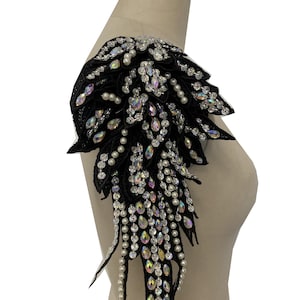 May include: Black shoulder piece with a cascading design of iridescent rhinestones and white pearls.