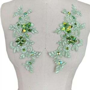 Puede incluir: Dos aplicaciones de encaje verde con pedrería verde iridiscente y transparente. Las aplicaciones son perfectas para añadir un toque de brillo a cualquier prenda.